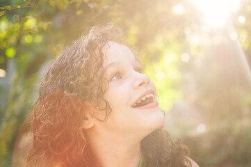 Portrait of beautiful curly hair girl smiling. Sunlight with flare.
