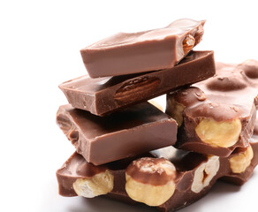 Pieces of tasty chocolate with hazelnuts on white background, closeup