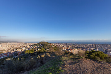 View of the city of Barcelona from the mountain on a sunny day. Urban landscape. Blue sky over the city.