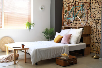 Interior of modern room with big bed and bicycle hanging on wooden wall