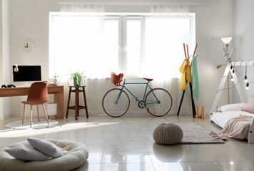 Interior of children's bedroom with modern bicycle and workplace