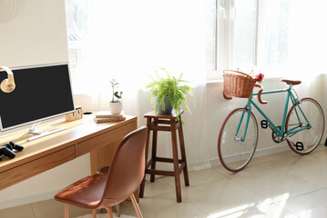 Interior of light room with modern bicycle and workplace