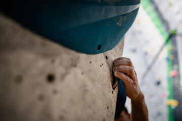 Male hand smeared with magnesium powder grabbing a hold of a climbing wall