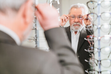 an elderly man chooses glasses in the optics salon.