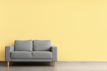 Comfortable sofa near yellow wall