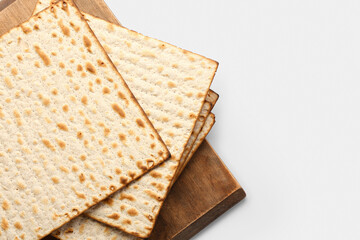 Wooden board with Jewish flatbread matza for Passover on white background
