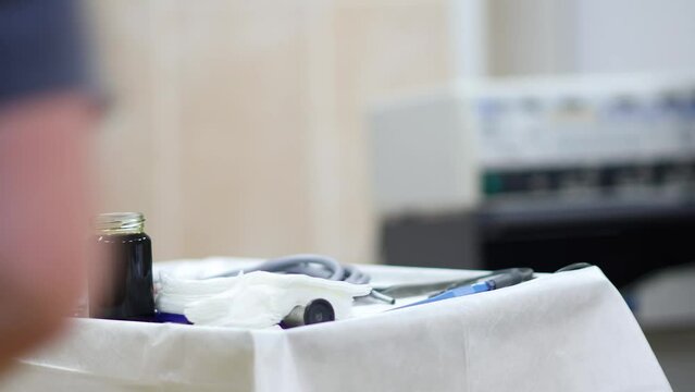 preparation of the surgical table for the operation, the assistant pours iodine to disinfect the surgical instruments.
