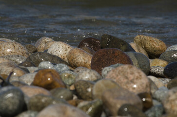 water beating on the colored stones on the shore of a lake