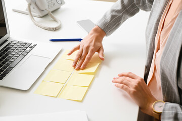 Young manager with sticky note papers at her workplace