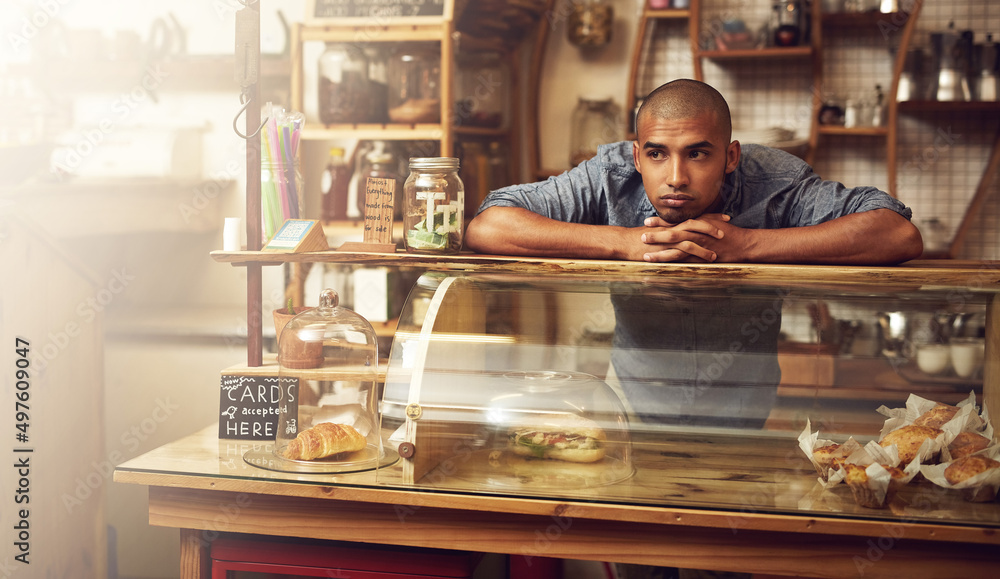 Poster where are all the customers. shot of a young man standing behind the counter of his store and lookin