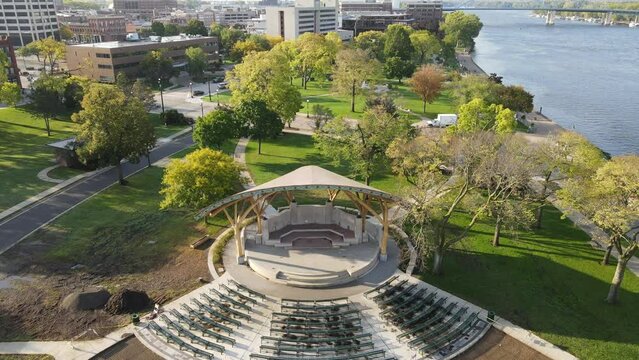 Close up then pan out over bandshell renovations in Riverside Park along the Mississippi River in Wisconsin. Constuction near complete of concrete. Downtown area in the distance. Big blue bridge.