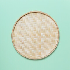 Round empty wicker straw basket with handles on light green background. View from above. Decorative interior items. copy space. Pastel soft colors