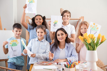 Cute children and teacher with painted pictures during master-class in art