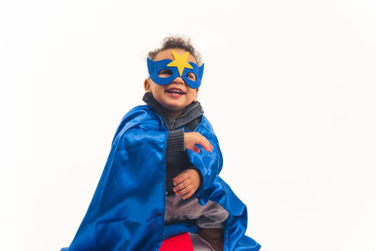 little African American curly boy with the blue costume of superhero laughing full shot studio shot white background copy space. High quality photo