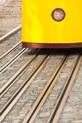 Tracks on Street with Passenger Car / Detail of rails and front section with headlamp of yellow tram (copy space) - 497610453