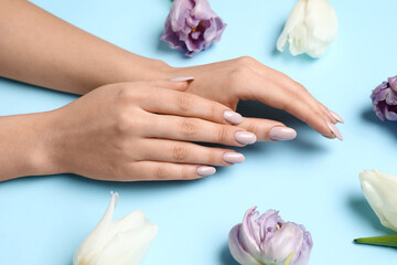 Obraz na płótnie Canvas Female hands with beautiful manicure and tulips on blue background, closeup