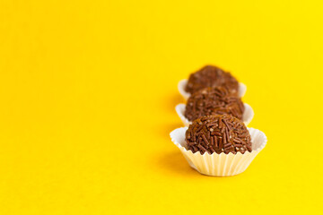 Brigadeiros lined up on a yellow background