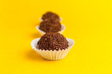 Brigadeiros lined up on a yellow background