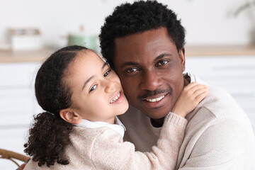 Obraz premium Happy African-American man and his little daughter hugging at home