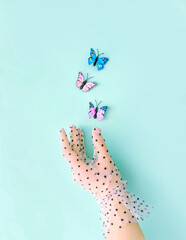 Spring creative idea with butterflies flying from a woman's hand on a pastel blue background. Retro romantic aesthetic summer concept of the 80's, 90's. Minimal surreal idea.