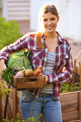 Have you gone green. Portrait of a happy young woman holding a crate full of freshly picked vegetables.