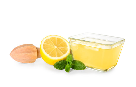 Bowl with fresh lemon juice, mint and juicer on white background