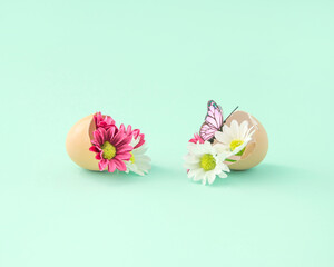 Easter and Spring creative eggshell arrangement with colorful flowers and pink butterfly on a pastel blue background. Retro romantic aesthetic Easter concept of the 80s, 90s. Minimal surreal idea.
