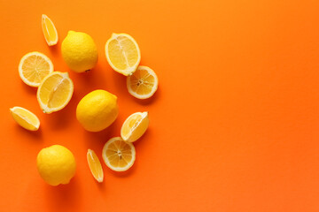 Ripe lemons and slices on orange background, top view