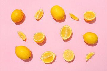 Many ripe lemons and slices on pink background, top view