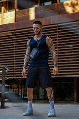 Caucasian sporty male with tattoos standing in the street