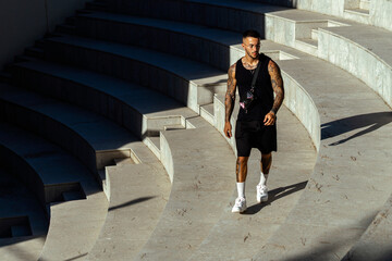 Caucasian sporty male with tattoos standing in the stone stair architecture