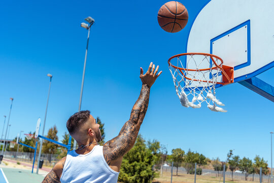 Sporty Caucasian male with tattoos playing basketball
