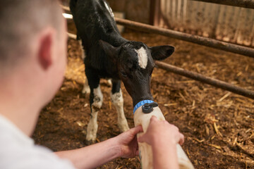 He needs his milk. Cropped shot of an unrecognizable young man feeding a calf in a dairy farm. © AS/peopleimages.com