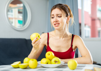 Obraz premium Portrait of diet tired young woman holding apples in her hands at home