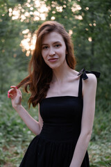 attractive young brunette woman in a black dress posing in the forest. freedom. fashion portrait