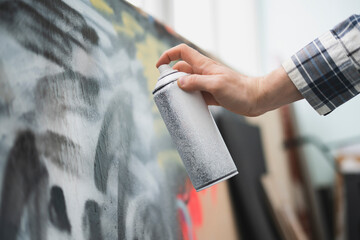 hand holding spray paint can, artist doing graffiti art on the wall