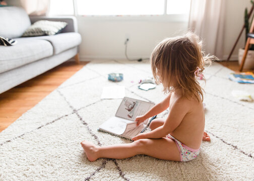 girl sits on floor with book
