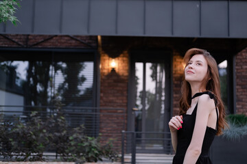 confident single woman near her new home. brown and black modern building. happy carefree suburb life