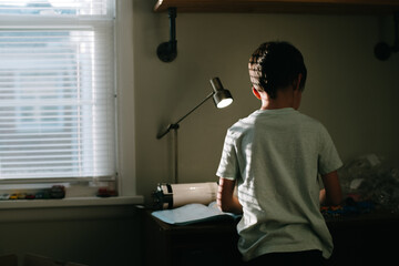 boy works at desk with lamp