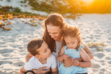 Mother sitting in sand with young children