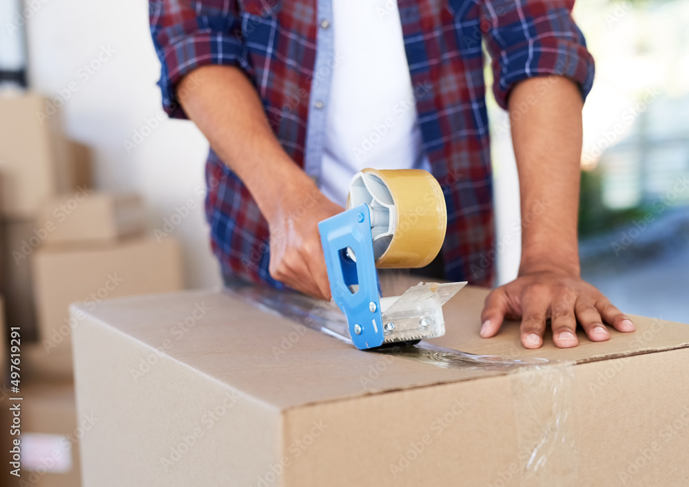 Poster safe and sealed. shot of an unidentifiable man using a tape dispenser to close a box while moving ho