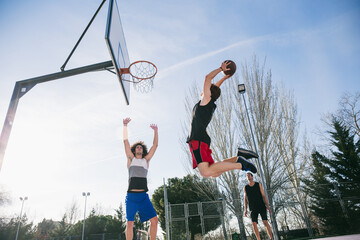 People in sunlight playing basketball 