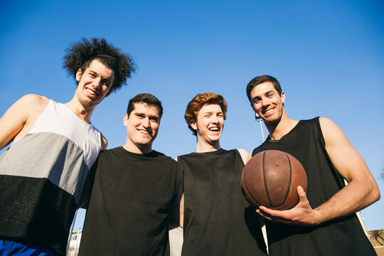 Young cheerful basketball players posing together 