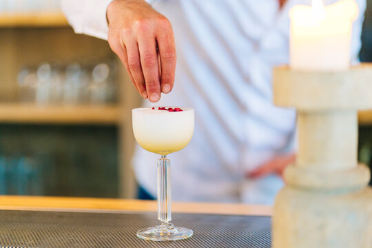 Faceless bartender adding ingredients in cocktail on bar counter