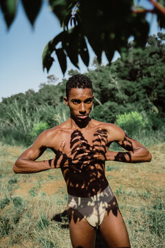 Portrait of expressive male dancer in nature with tree shadows 