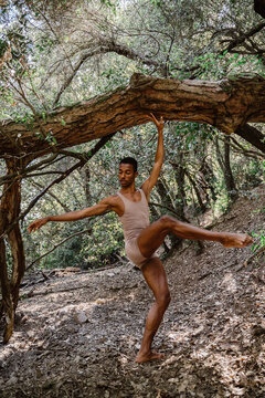 Portrait of expressive male dancer in forest in tree
