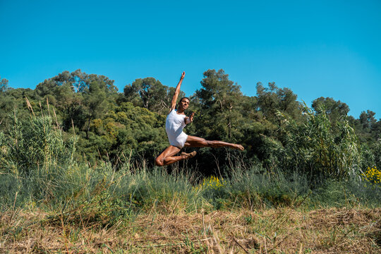Portrait of expressive male dancer in nature jumping and moving