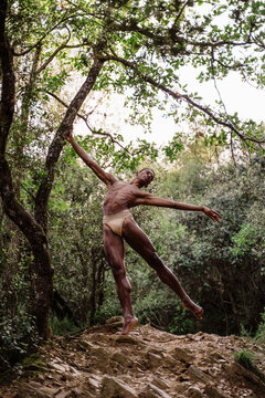 Portrait of expressive male dancer in forest in tree