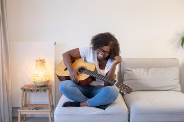 black woman with guitar laughing at home