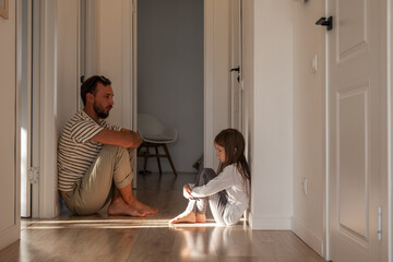 Upset daughter sitting in corridor with father